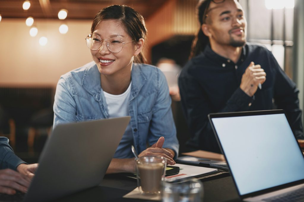Smiling Asian businesswoman meeting with coworkers in an office
